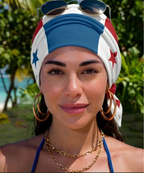 Woman wearing a colorful headscarf with a star design, sunglasses on her head, and gold jewelry in a tropical setting.