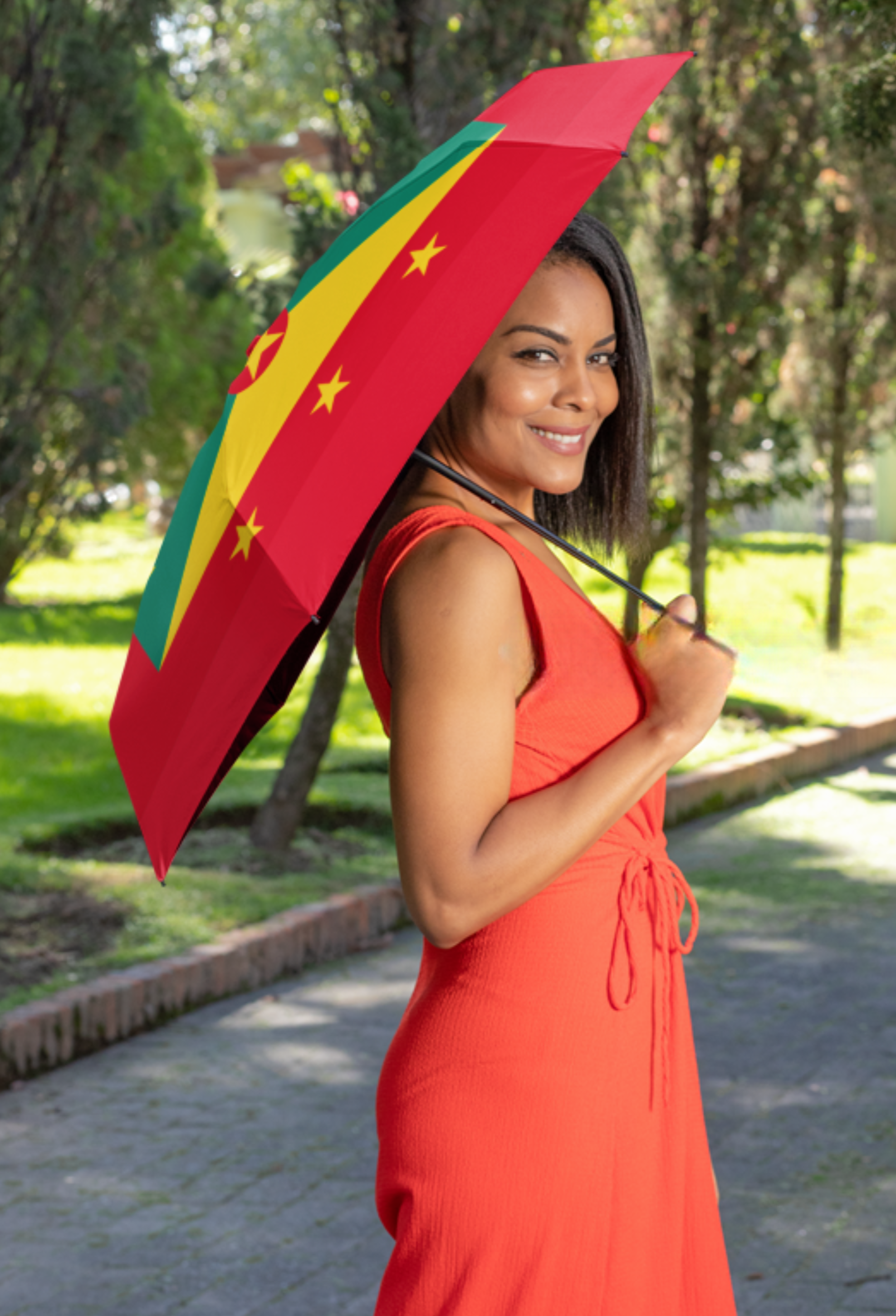 Woman holding a red, yellow, and green umbrella with star patterns outdoors.