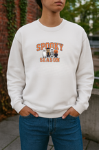 Person wearing a white sweatshirt with 'Spooky Season' text and ghost graphic on a blurred background
