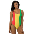 A confident Black woman models the swimsuit in a bold stance with natural curls and hoop earrings, shot against a vibrant blue background that complements the colors of the suit.